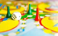 board-games-for-the-home-yellow-green-and-red-plastic-chips-and-dice-on-board-games-for-children-selective-focus