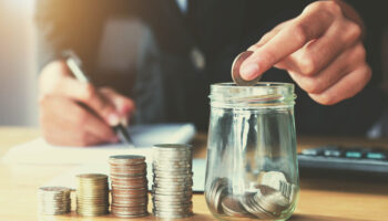 saving-money-woman-hand-putting-coin-in-jug-glass-concept-business-finance